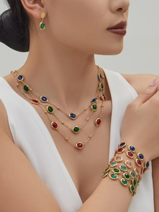 Model wearing a luxury layered gold necklace and bracelet set with colorful faceted stones