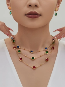 Macro detail of multi-layered 18k gold necklace with colorful oval gemstone settings
