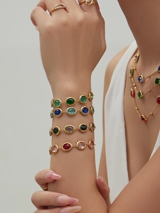 Close-up of gold layered necklaces and colorful faceted gemstone bracelets on a model