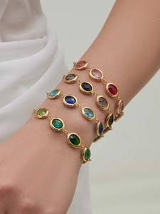Macro shot of 18k gold plated bracelets with vibrant oval faceted gemstones on wrist