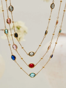 Detalle de collar de capas doradas con piedras ovaladas de colores y cuentas de metal