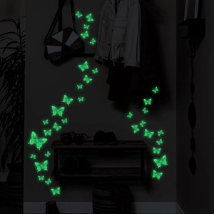 Detailed view of luminous butterfly wall stickers glowing bright green in a dark room