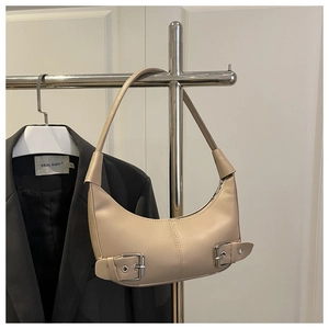 Detail view of beige crescent hobo bag featuring decorative silver metal buckles on the side
