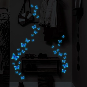 Luminous blue PVC butterfly wall stickers glowing in a dark bedroom setting