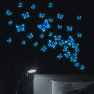 Glow-in-the-dark blue butterfly wall stickers glowing in a dark bedroom setting