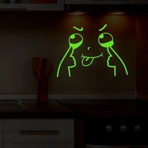 Luminous green emoji wall sticker glowing in a dark kitchen setting on a tiled wall