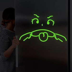 Glow-in-the-dark emoji sticker featuring a funny cartoon face on a fridge door
