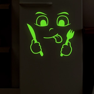 Close-up of glowing emoji wall sticker with fluorescent green cutlery in the dark