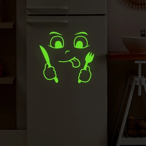 Luminous green emoji stickers with knife and fork glow in the dark on fridge surface