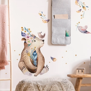 Detail of watercolor cartoon bear and bird wall stickers in a cozy nursery room setting