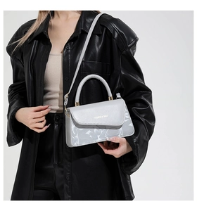 Détail du sac bandoulière en cuir gris avec motif floral blanc et finitions dorées