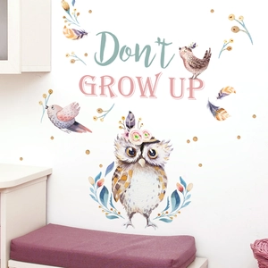 Detail of watercolor owl wall sticker with birds and Don't Grow Up slogan on a white wall