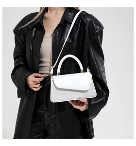 Detail van witte lederen crossbodytas met subtiel bloemenpatroon en goudkleurige accenten