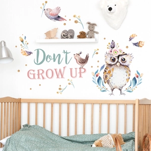 Detail of watercolor owl wall sticker with Don't GROW UP text in a cozy nursery room