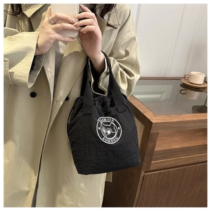 Detail of waterproof nylon drawstring bucket bag with fashion logo and top handle grip