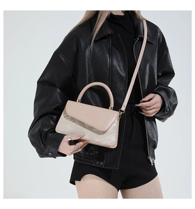 Detail van de elegante beige vierkante tas met marmerpatroon en gouden gesp