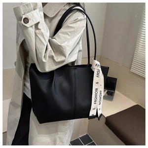 Detail of black tote bag with vertical stitching and decorative slogan ribbon strap