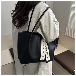 Detail view of large black minimalist tote bag with fashion printed strap on shoulder