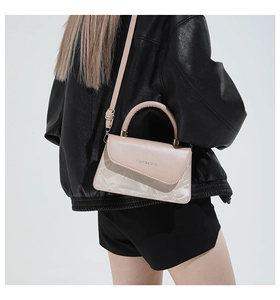 Detalle de bolso cuadrado rosa albaricoque con textura geométrica y texto decorativo