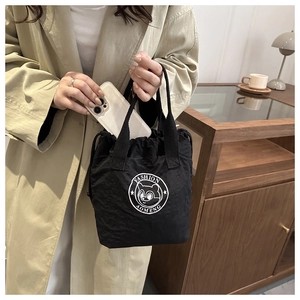 Detailed view of black waterproof nylon bucket bag featuring cartoon bear logo and drawstring