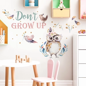 Detail of watercolor owl wall sticker with Don't Grow Up text in a kids bedroom