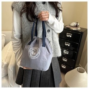 Detail of grey waterproof drawstring bucket bag with logo and blue textile handles