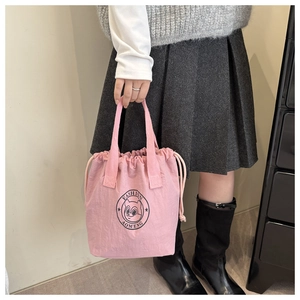Pink drawstring bucket bag with squirrel logo held by model in casual college style