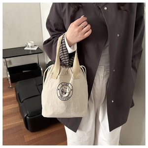 Close-up of cream nylon bucket bag featuring drawstring closure and plaid lining detail