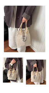Detail view of beige drawstring insulated lunch bag with portable handle and cat logo