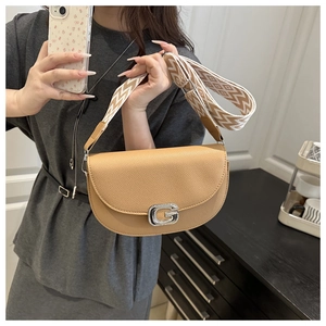 Detail of tan saddle bag featuring a rhinestone-encrusted G buckle and woven strap