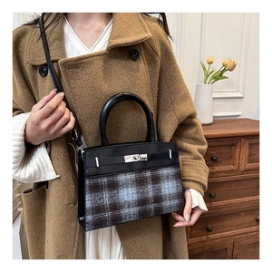Detail of the contrast plaid handbag with metal twist lock and textured fabric finish