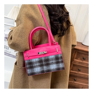 Detail of trendy crossbody bag with pink leather and gray plaid contrast on model