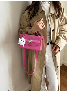 Close-up of fuchsia crossbody bag with monogram texture and golden metal lock detail