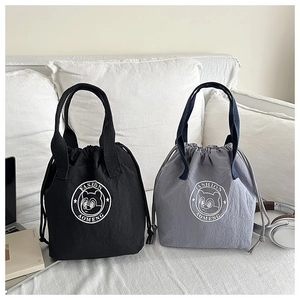 Detail of waterproof drawstring bucket bags in black and grey on a sofa with cozy props