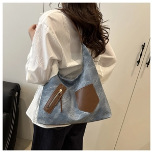 Detail of blue canvas tote bag with brown leather pockets and shoulder strap