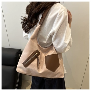 Detail of a beige tote bag with brown leather pocket and long zipper tassel decoration