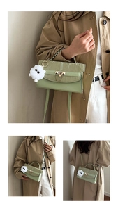Detail of light green pleated handbag with metal lock, chain, and plush dog charm
