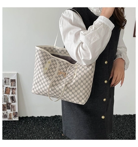 Detailed shot of large tote bag with M-letter monogram and metallic bow charm