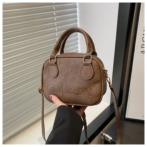 Detail of vintage brown leather shell bag featuring embossed logo and cylinder handles