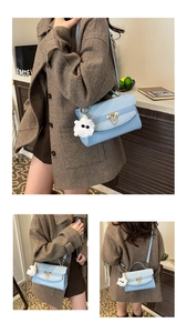 Detail view of light blue textured handbag with gold lock and plush toy charm