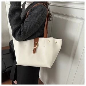 Detail of white leather tote bag with brown strap and golden oval metal buckle decoration