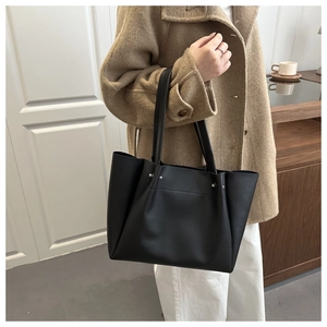 Detail of minimalist black tote bag with silver studs and smooth leather texture