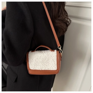 Detailed back view of a plush wool saddle bag with brown leather and gold hardware