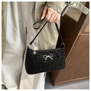 Detail of leopard print underarm bag with gold bow clasp and floral zipper pull