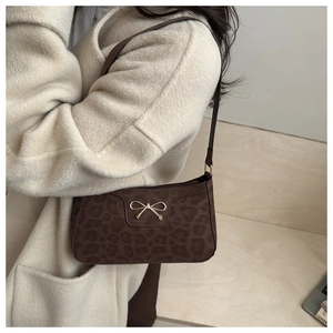 Detail of leopard print suede shoulder bag featuring a gold bow accent and zip closure