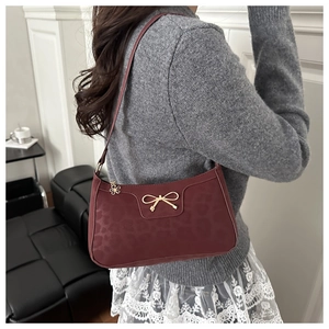 Detail of burgundy leopard print shoulder bag with gold bow clasp and flower charm