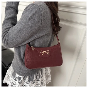 Close-up of burgundy underarm bag featuring leopard pattern and golden bow detail