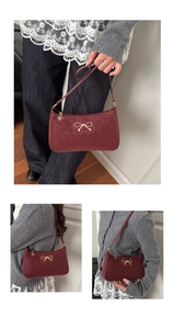 Detail of burgundy shoulder bag with leopard embossed texture and golden bow hardware