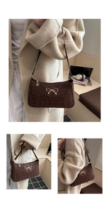 Detail of leopard print suede shoulder bag with golden bow clasp and floral zipper charm