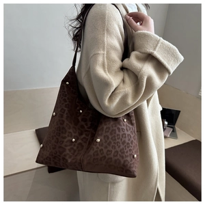 Dettaglio borsa shopper leopardata con borchie dorate su superficie in velluto